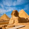 Egyptian Great Sphinx full body portrait with head, feet with all pyramids of Menkaure, Khafre, Khufu  in background on a clear, blue sky day in Giza, Egypt empty with nobody. copy space
